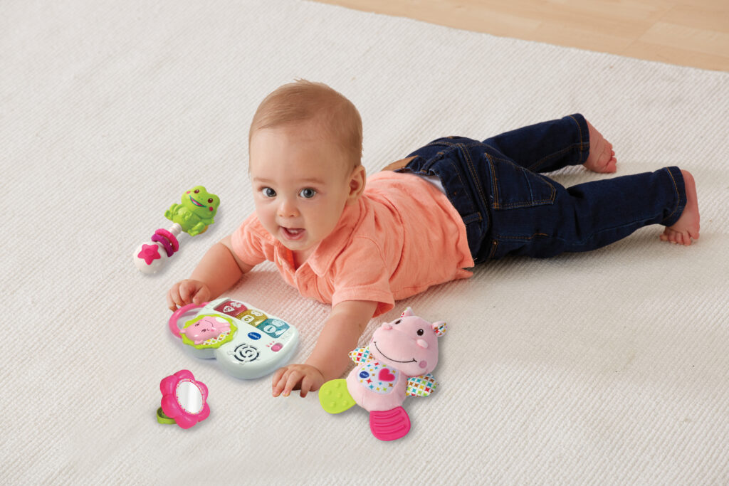 Auf dem Bauch liegendes Baby mit Produkten aus dem VTech Babys Geschenkset