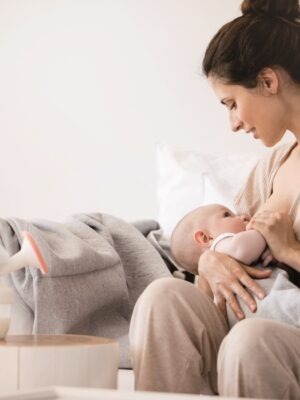 Mama sitzt auf dem Sofa und stillt ihr Baby