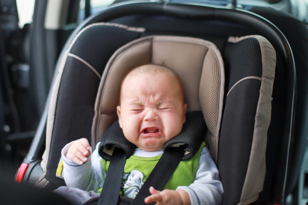 1.	Baby sicher in Babyschale bei Autofahrt – Ein entspanntes Baby, das sicher in einer Babyschale während einer Autofahrt sitzt, mit Spielzeug zur Ablenkung.