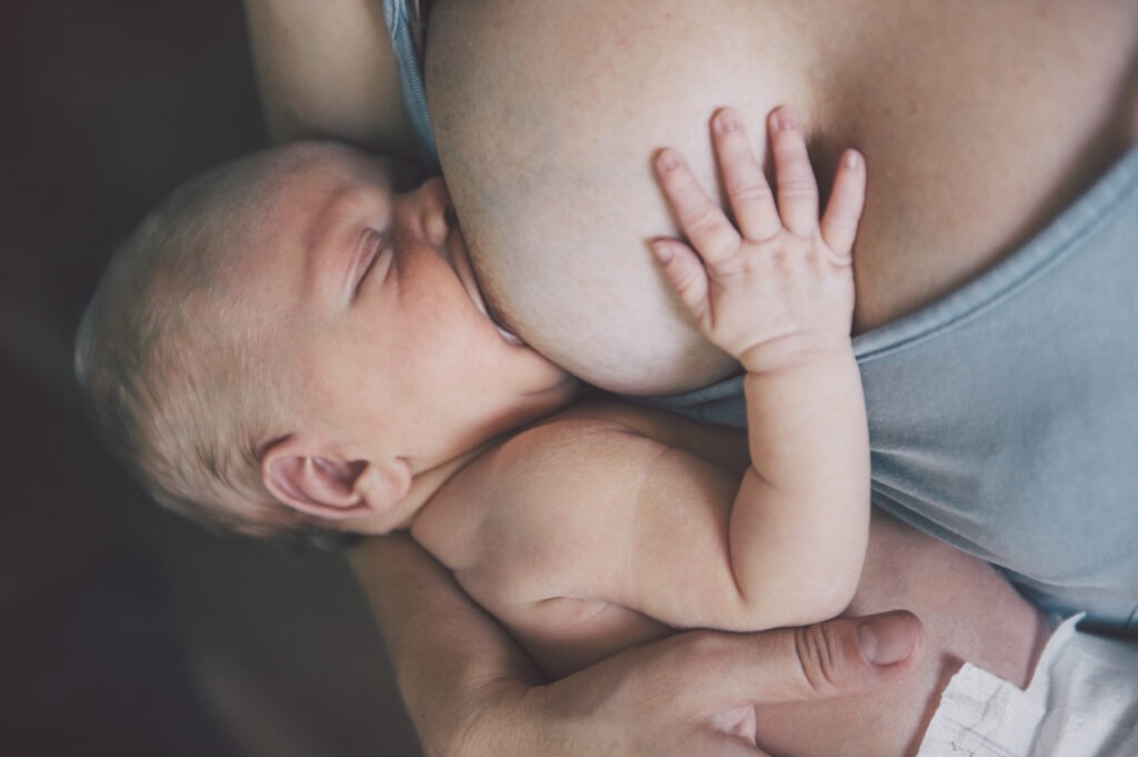 Mutter stillt Baby in entspannter Position, der Rückflusseffekt beim Stillen schützt das Baby.