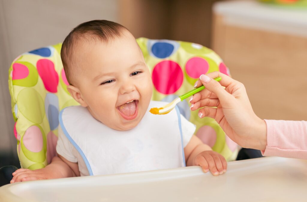 1.	Mutter füttert Baby mit Löffel – Wie viel sollte mein Baby essen im ersten Jahr