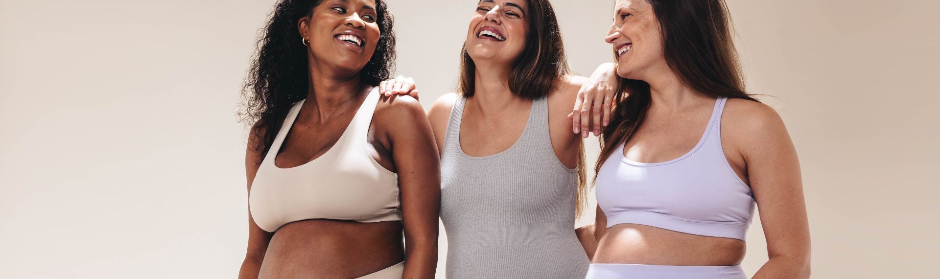 Drei werdende Mamas, die Zeit miteinander verbringen und lachen. Man sieht ihnen ihre körperlichen Veränderungen in der Schwangerschaft an.