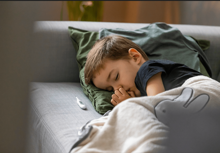 Mutter misst die Temperatur ihres Kindes mit einem Infrarot-Thermometer – Fieber bei Kindern schnell und einfach erkennen. Ein fieberndes Kind, das liebevoll von seiner Mutter umsorgt wird, mit einem Glas Wasser in der Hand – Zuwendung und Flüssigkeitszufuhr bei Fieber.