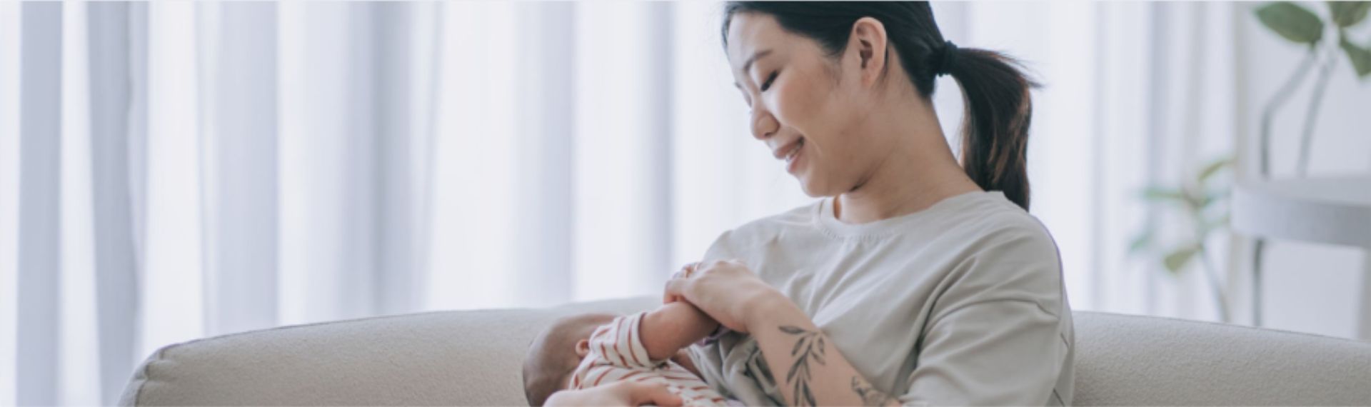 Eine Mutter stillt ihr Kind in einem leicht abgedunkelten Raum, die beiden haben eine innige und positive Stillbeziehung.