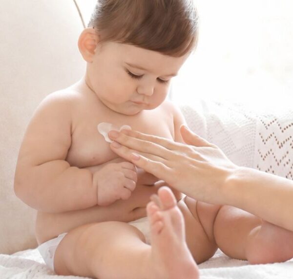 Mutter cremt ihr Baby sanft ein.